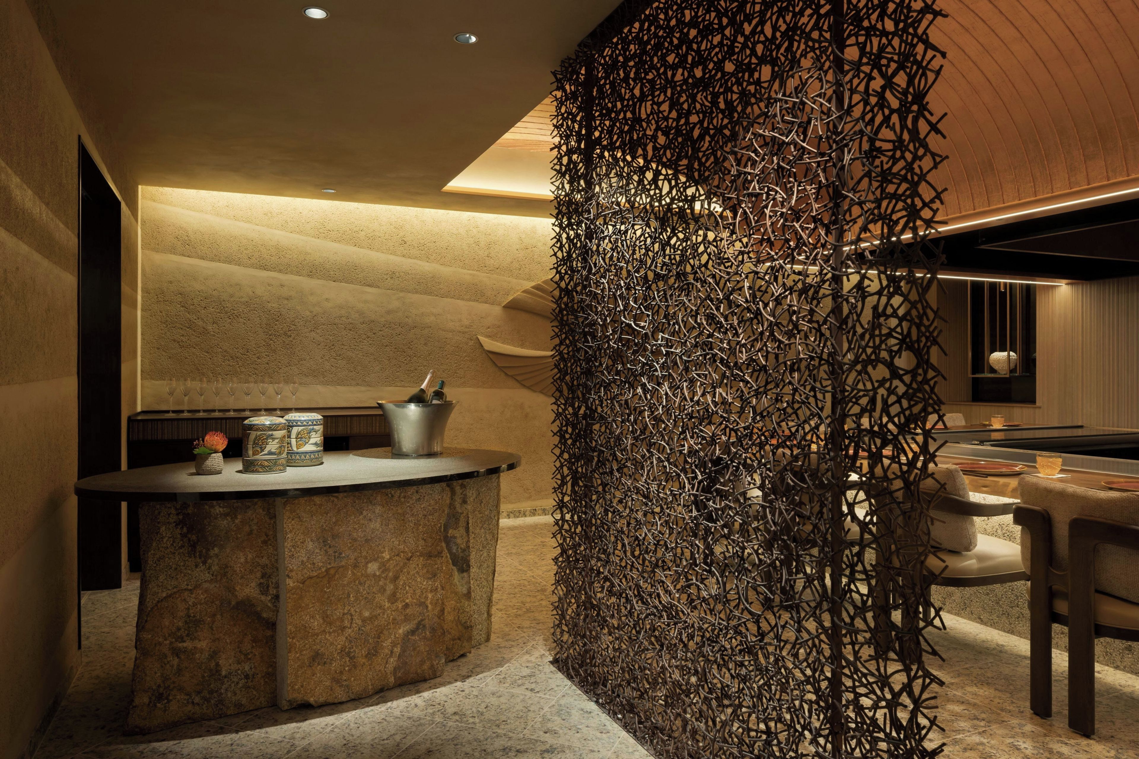A modern interior with a stone bar, a decorative metal wall, and a pool table.