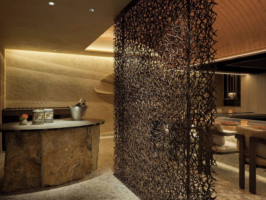 A modern interior with a stone bar, a decorative metal wall, and a pool table.