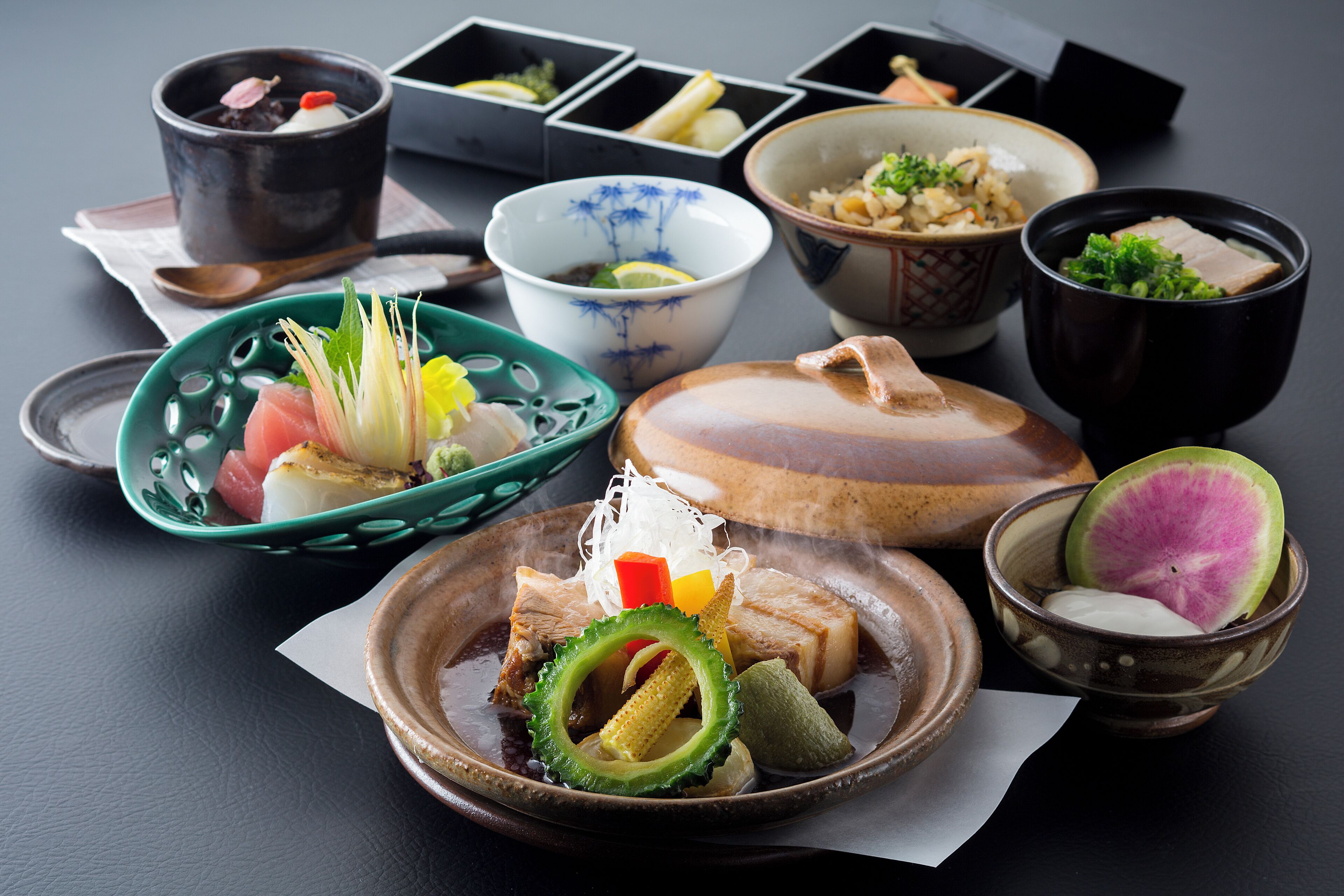A variety of Japanese dishes including a bowl of soup, a plate with meat and vegetables, and several small bowls with different foods.