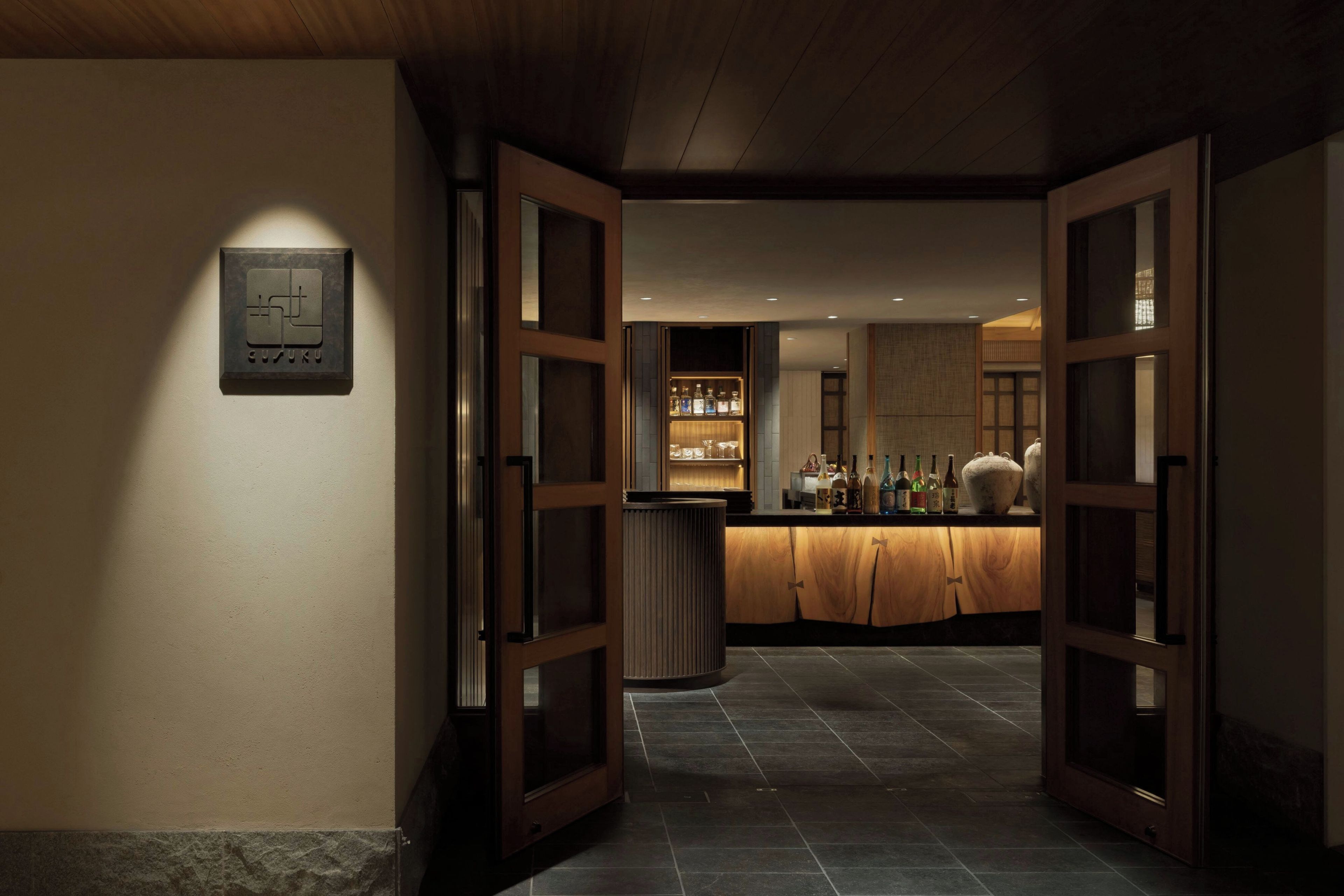 A hotel lobby with a reception desk, a display case with bottles, and a sign on the wall.
