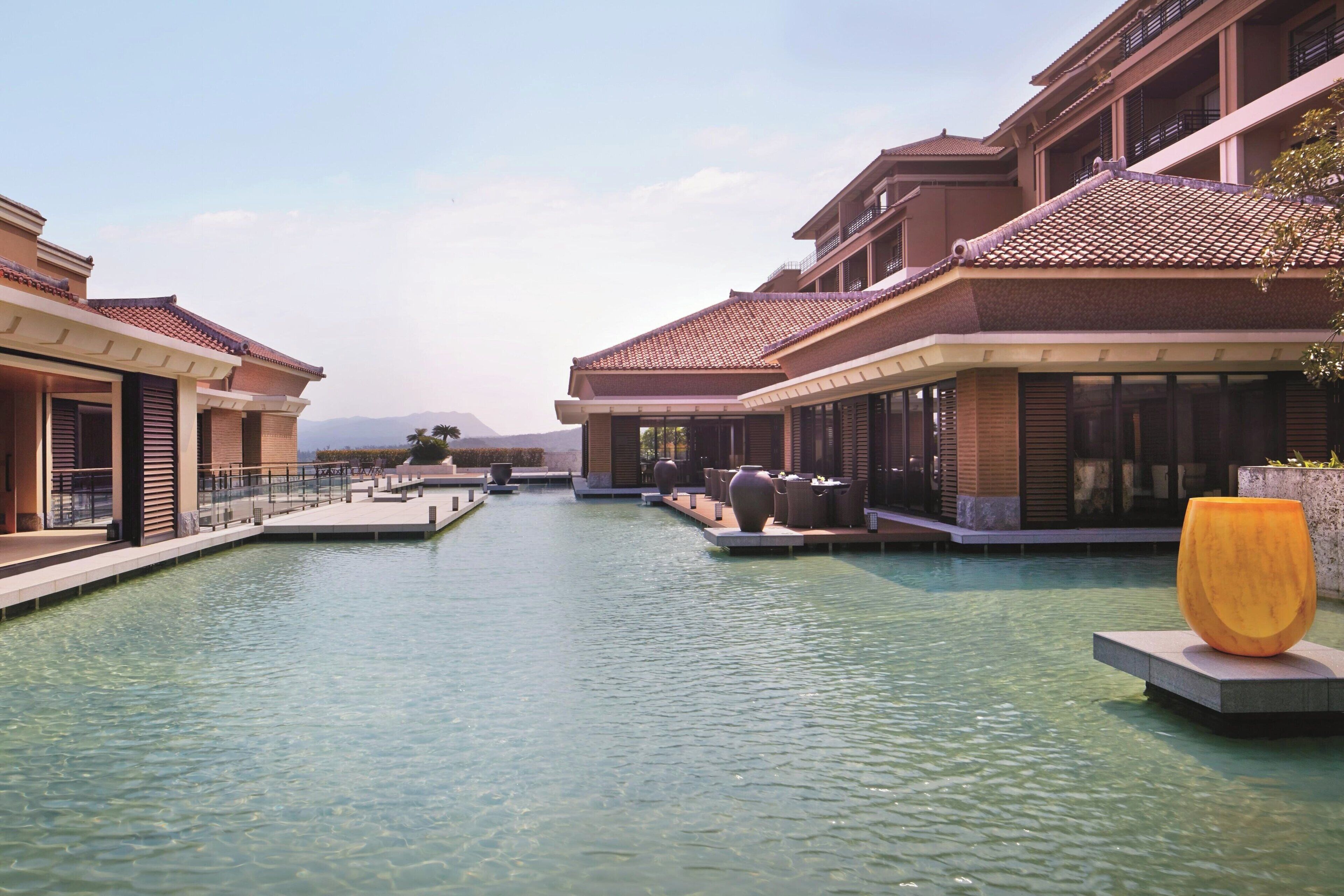 A resort with a central water feature, multiple buildings with balconies, and outdoor seating areas.