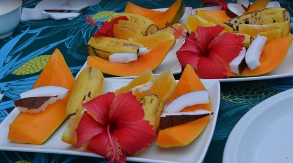 A table with fruit skewers and a hibiscus flower.