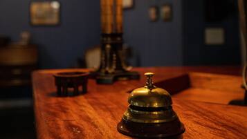 Una mesa de madera con una campana de bronce y una lámpara de mesa.