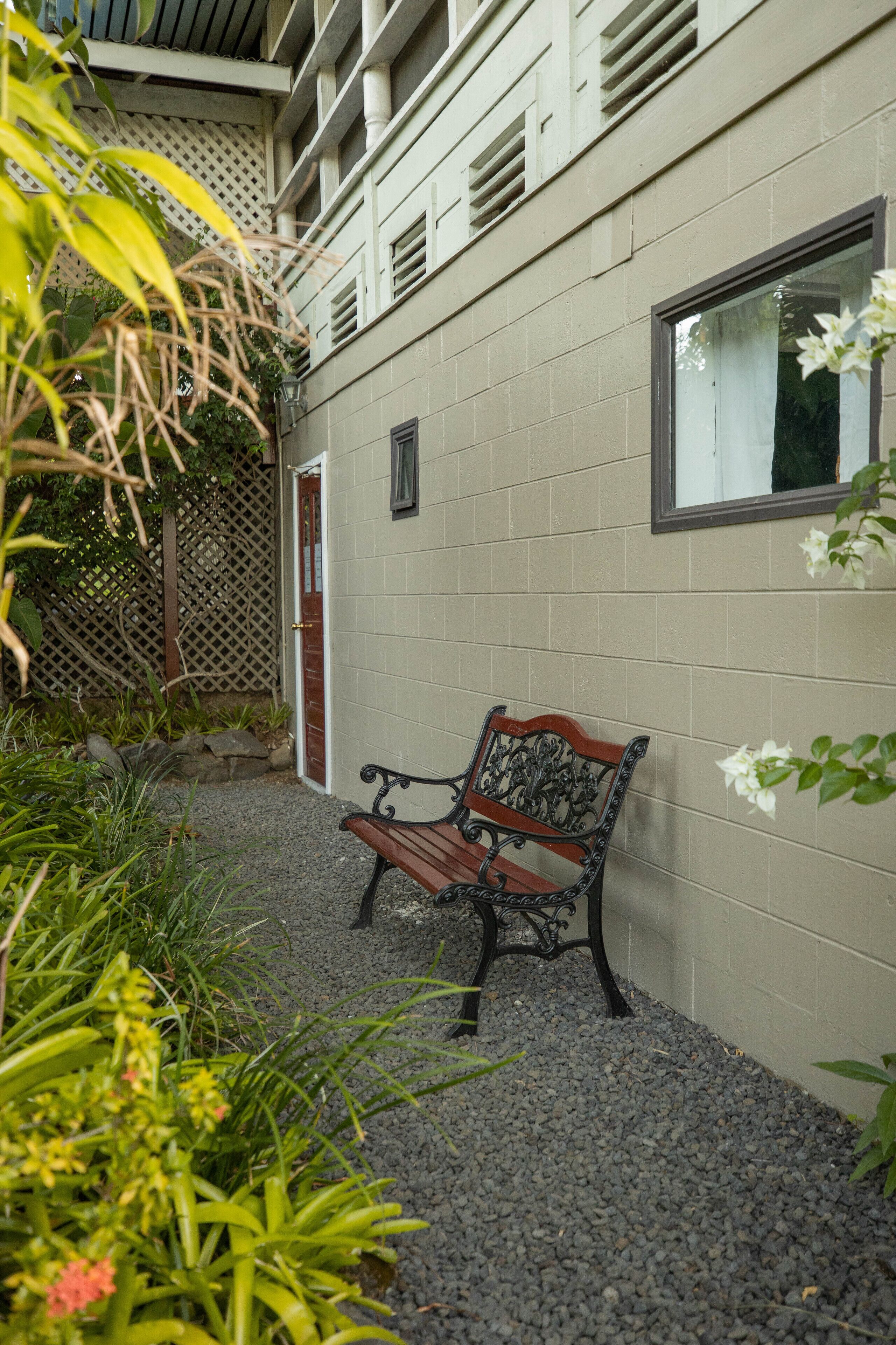 A bench in a garden area with a building in the background.
