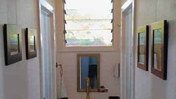 A narrow hallway with a white sink, a mirror, and framed pictures on the walls.