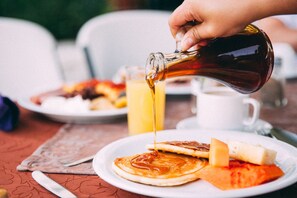 A breakfast setting with pancakes, cheese, and a bottle of syrup being poured.