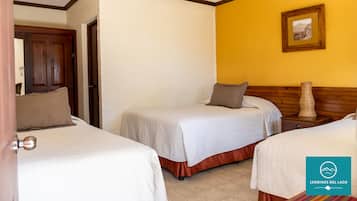 Habitación de hotel con dos camas, un cabecero de madera, un cuadro en la pared y una puerta.