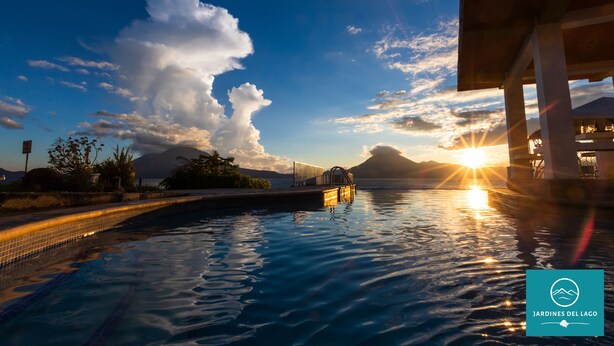 Un espace piscine offrant une vue sur le coucher de soleil et les montagnes en arrière-plan.