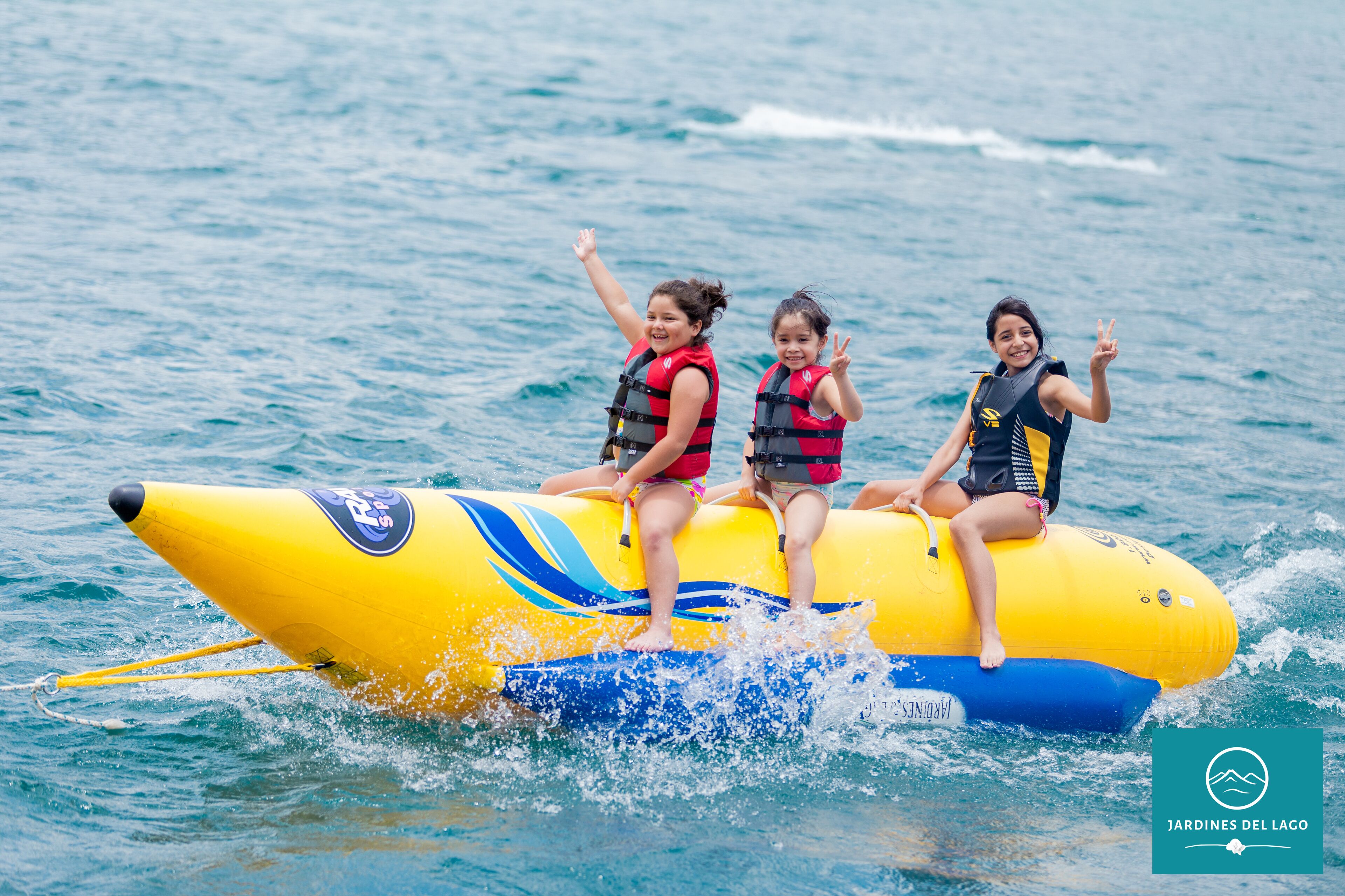 Trois personnes se trouvent sur un radeau gonflable jaune et bleu, sur l’eau.
