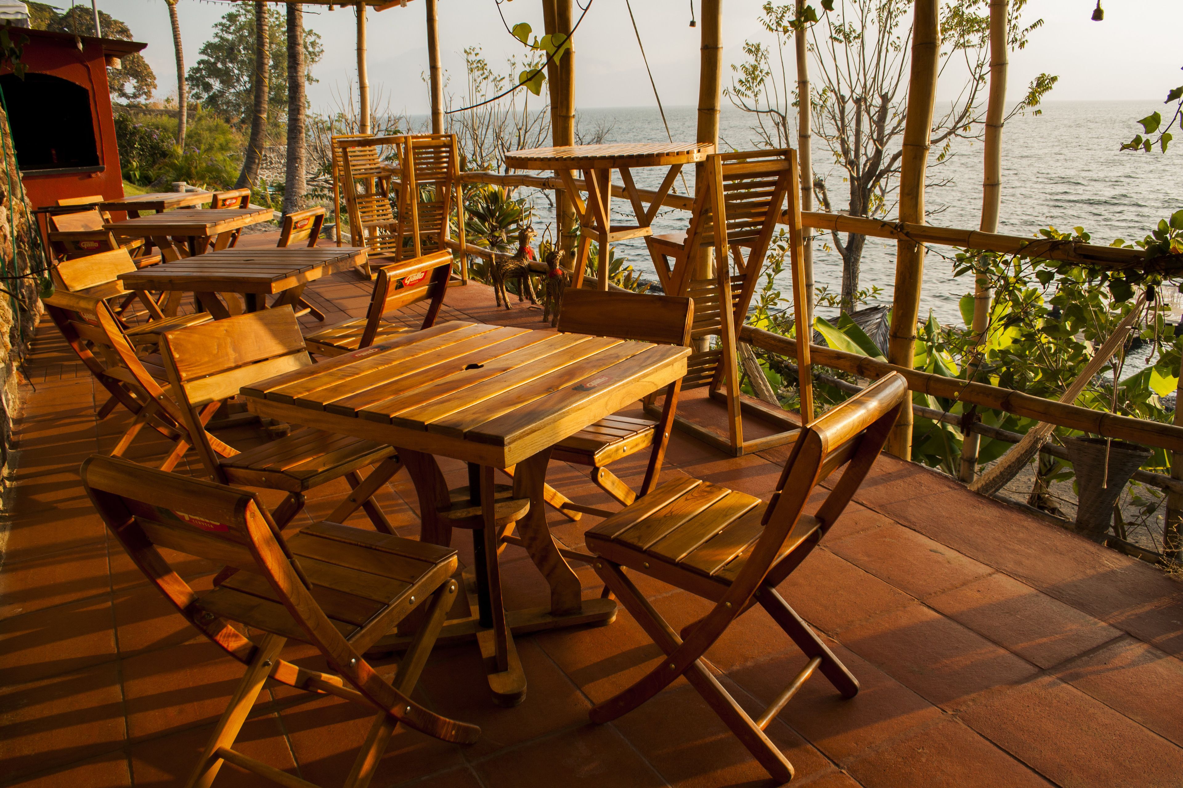 Una terraza de madera al aire libre con mesas y sillas, con vista a una masa de agua.