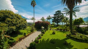 Un jardin bien entretenu, avec un chemin de pierres, une végétation luxuriante et des palmiers.