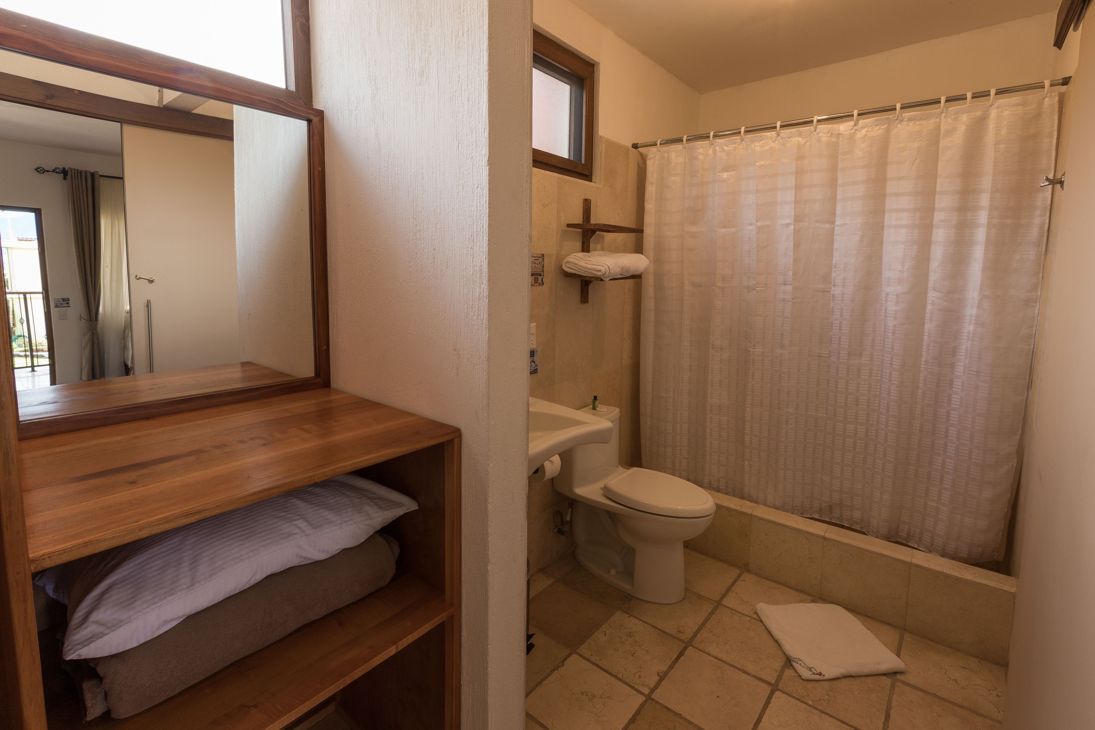 Ein Badezimmer mit Holzregal, Toilette und Duschvorhang.