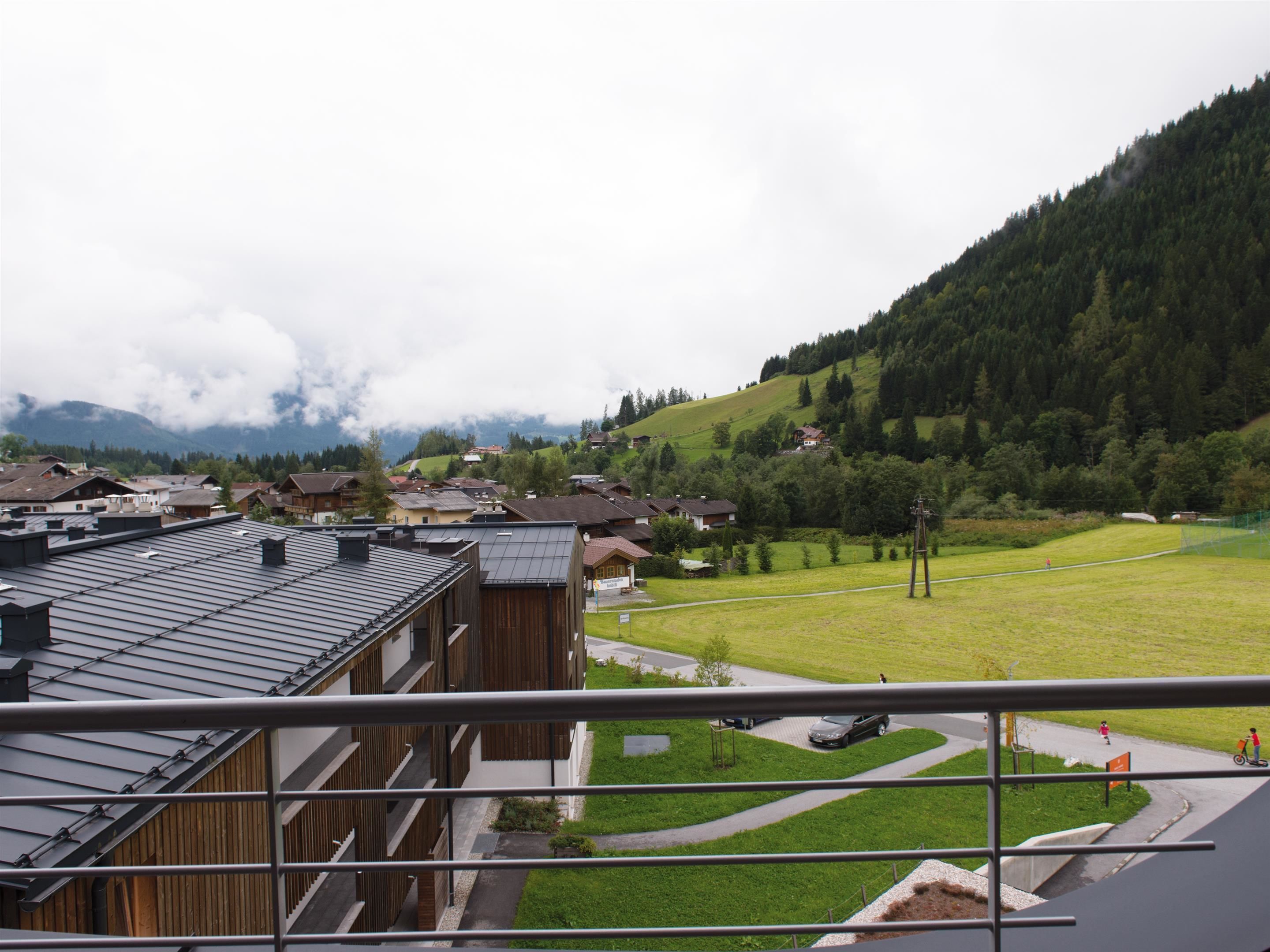 A residential area with houses, a green field, and a mountain in the background.