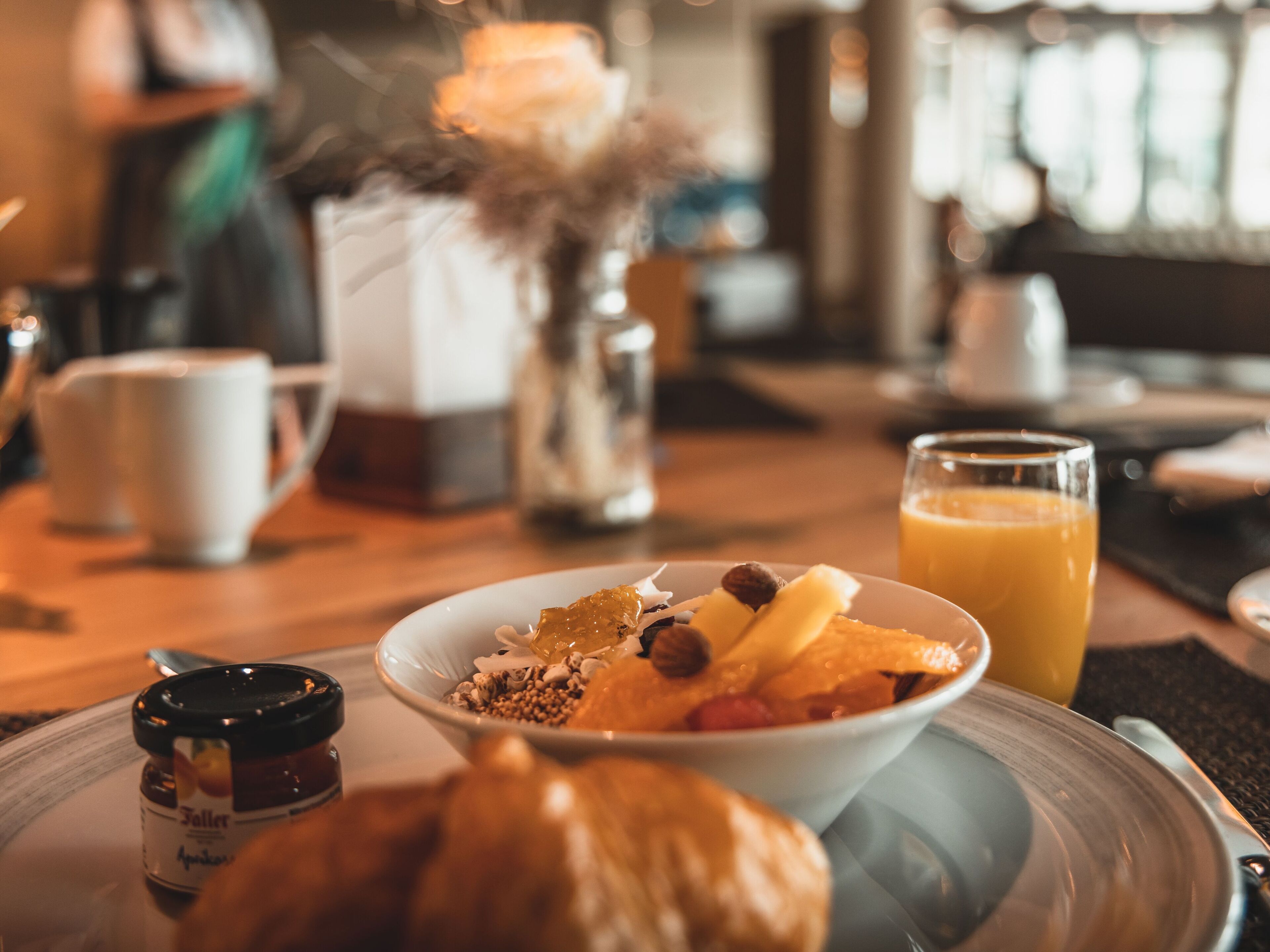 A breakfast setting with a plate of food, a glass of orange juice, and a jar of jam.
