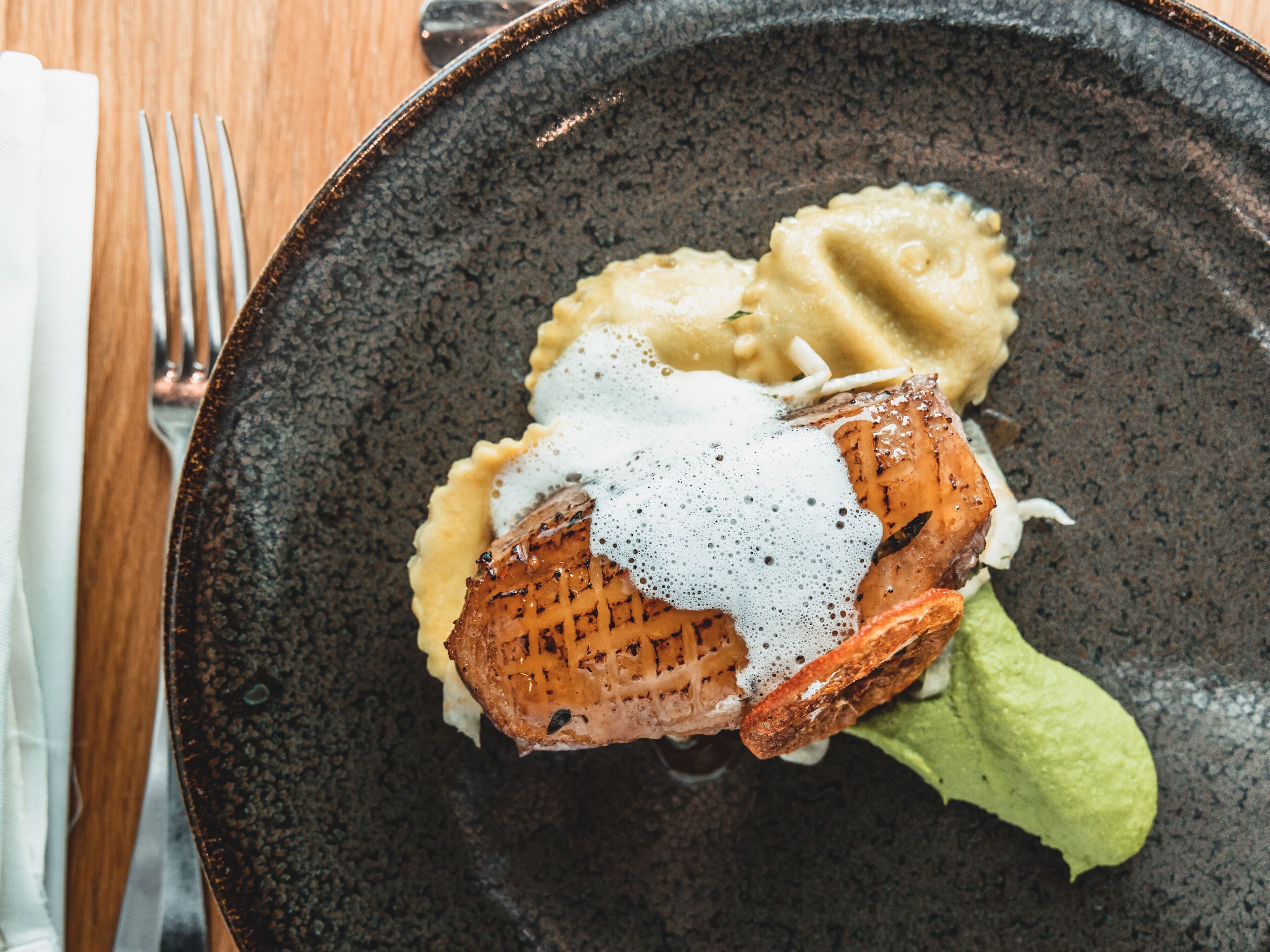 A plate with grilled meat, mashed potatoes, and a creamy sauce.