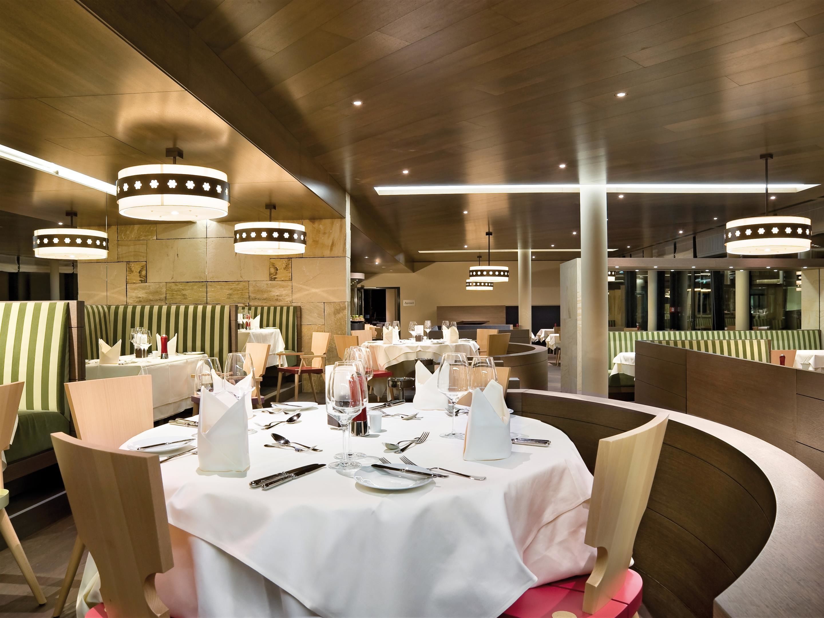 A restaurant with round tables set for dining, featuring white tablecloths and silverware.