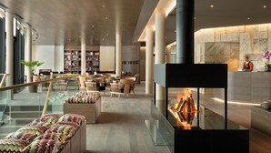 Eine moderne Lobby mit einem zentralen Kamin, einer Sitzecke und einer Bibliothek.