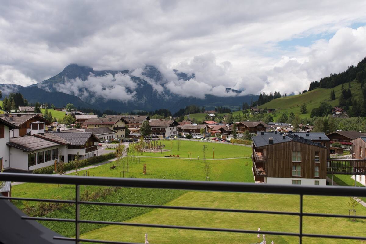 A residential area with houses, a green park, and mountains in the background.