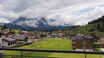 Un barrio residencial con casas, un parque verde y montañas al fondo.