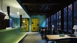Un restaurante moderno con una barra larga, varias mesas y sillas.
