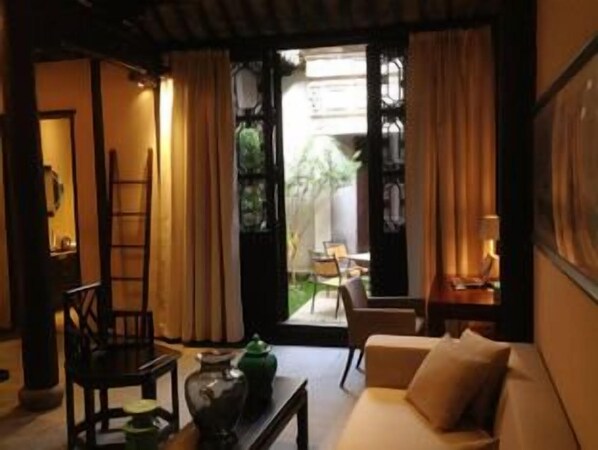 A cozy living room with a sofa, a coffee table, and a chair. There is a ladder leaning against the wall and a window with curtains.