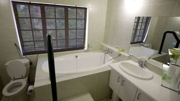 A bathroom with a toilet, bathtub, and two sinks.