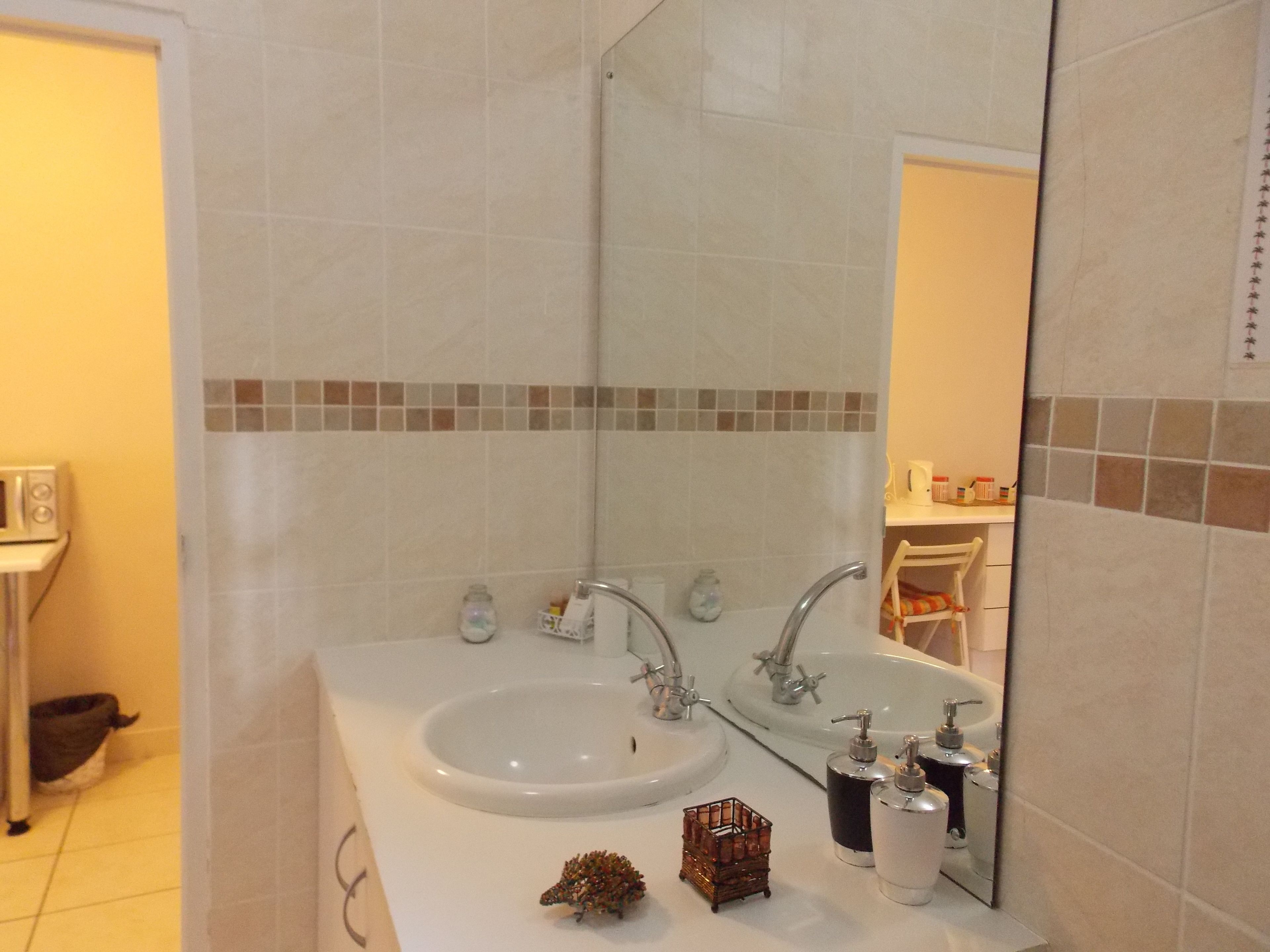 Un baño con dos lavamanos, un espejo y artículos de aseo.
