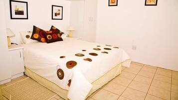 A neatly arranged bedroom with a bed, pillows, bedside tables, and wall art.