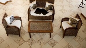 Ein Zimmer mit einem zentral platzierten Korbsessel-Sofa, zwei passenden Sesseln und einem kleinen Holztisch.