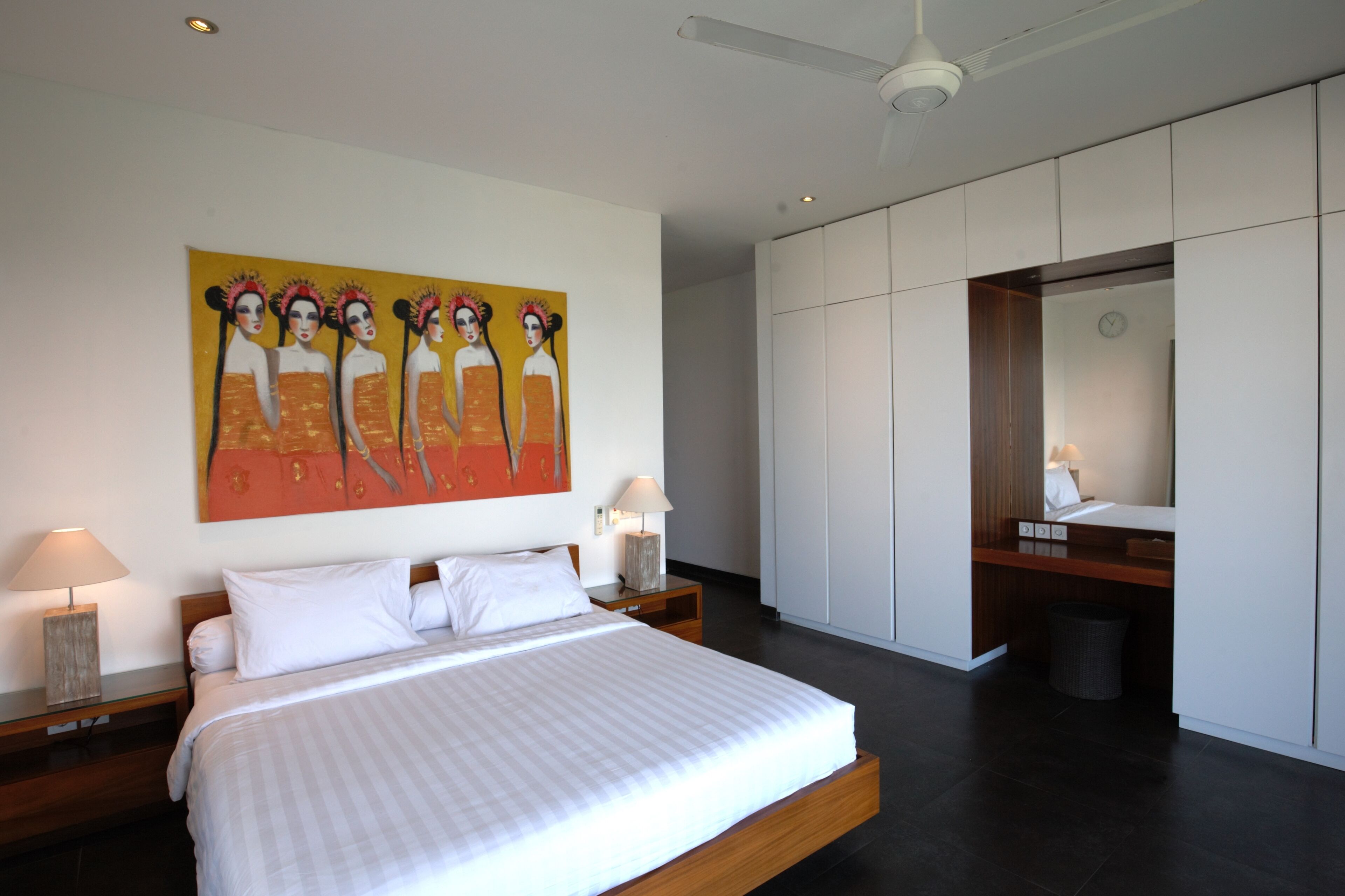 A modern bedroom with a large bed, a painting on the wall, and a wardrobe.