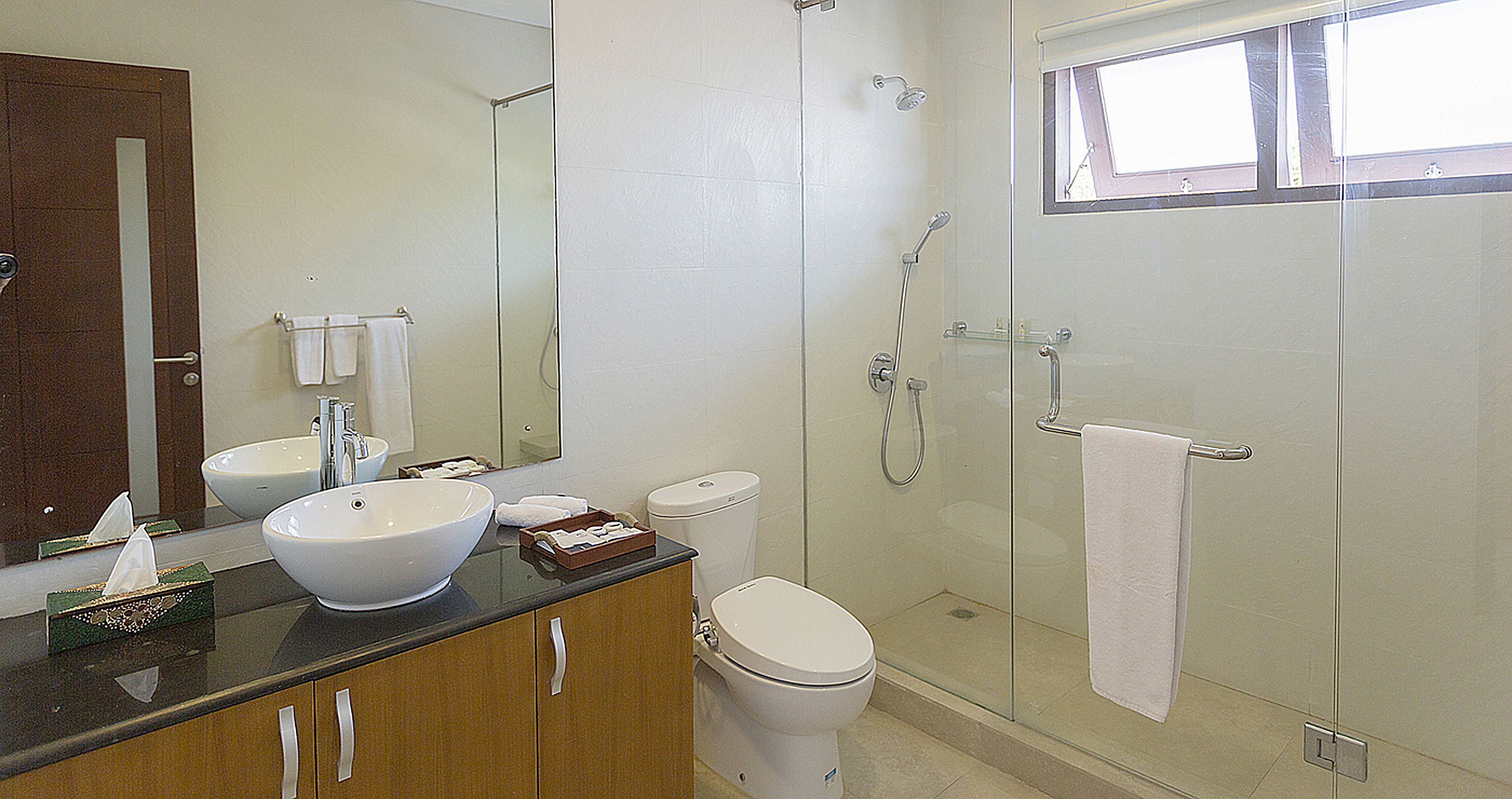 A bathroom with a large sink, toilet, and a glass-enclosed shower.