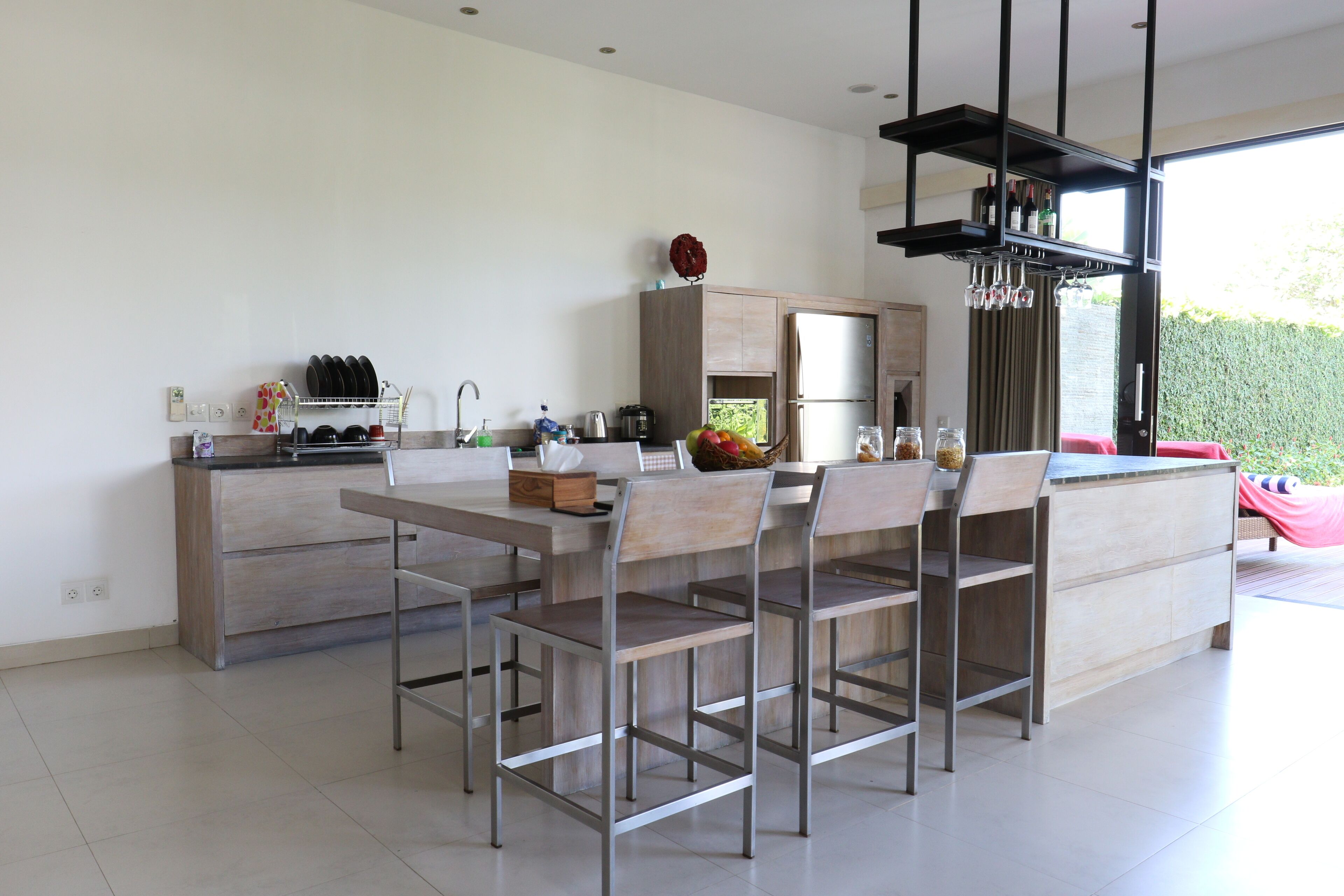 Una cocina moderna con una isla central, electrodomésticos de acero inoxidable y un comedor con sillas de metal.