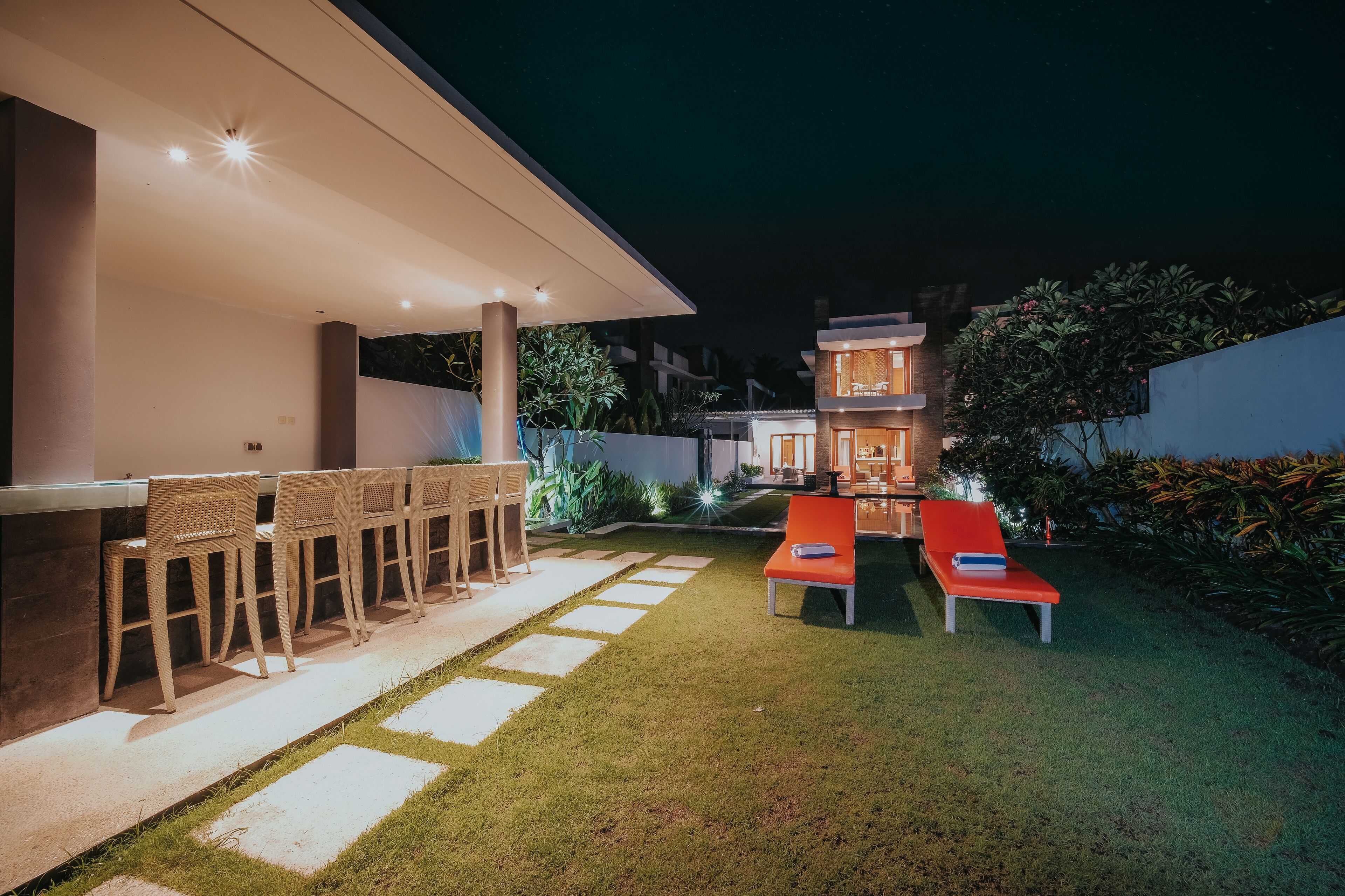 An outdoor patio with a bar, seating, and a well-maintained lawn.