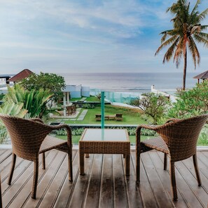 A wooden deck with wicker furniture overlooking a garden and the ocean. - Bali Diamond Villas (Gianyar)