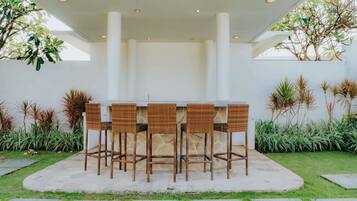 An outdoor bar area with wicker chairs and a central bar.