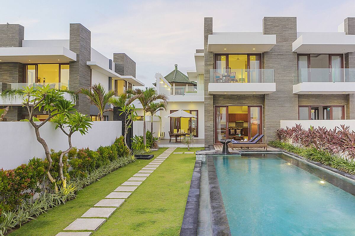 A modern residential complex with a swimming pool, well-maintained lawn, and multiple balconies.