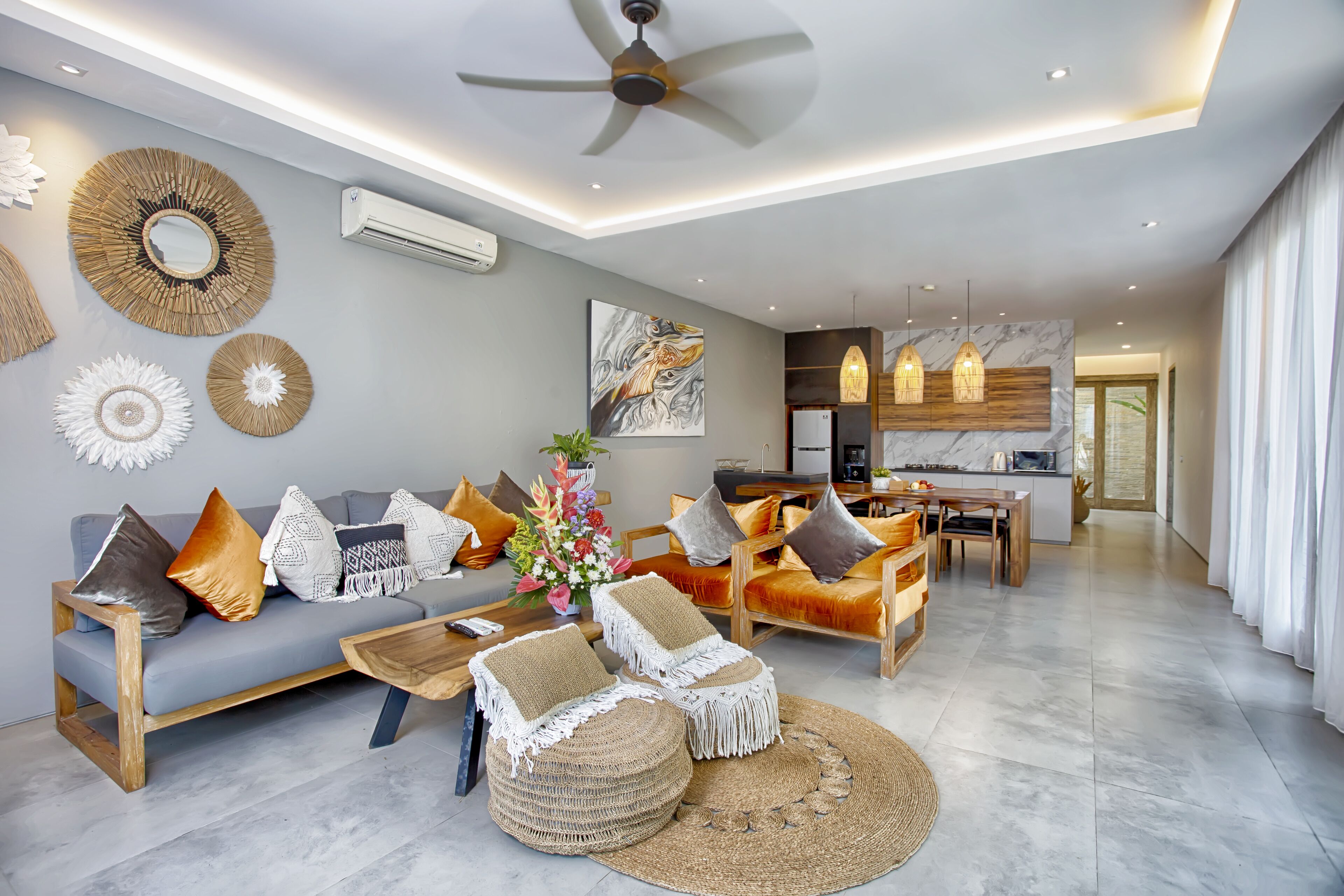 A modern living room with a sofa, ottomans, and a coffee table. There is a dining area with wooden chairs and a table.