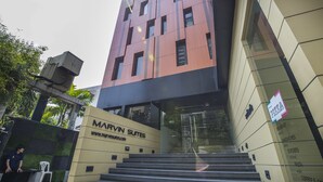 Un immeuble portant une enseigne « Marvin Suites », caractérisé par un design moderne alliant verre et béton, et un escalier menant à l’entrée.