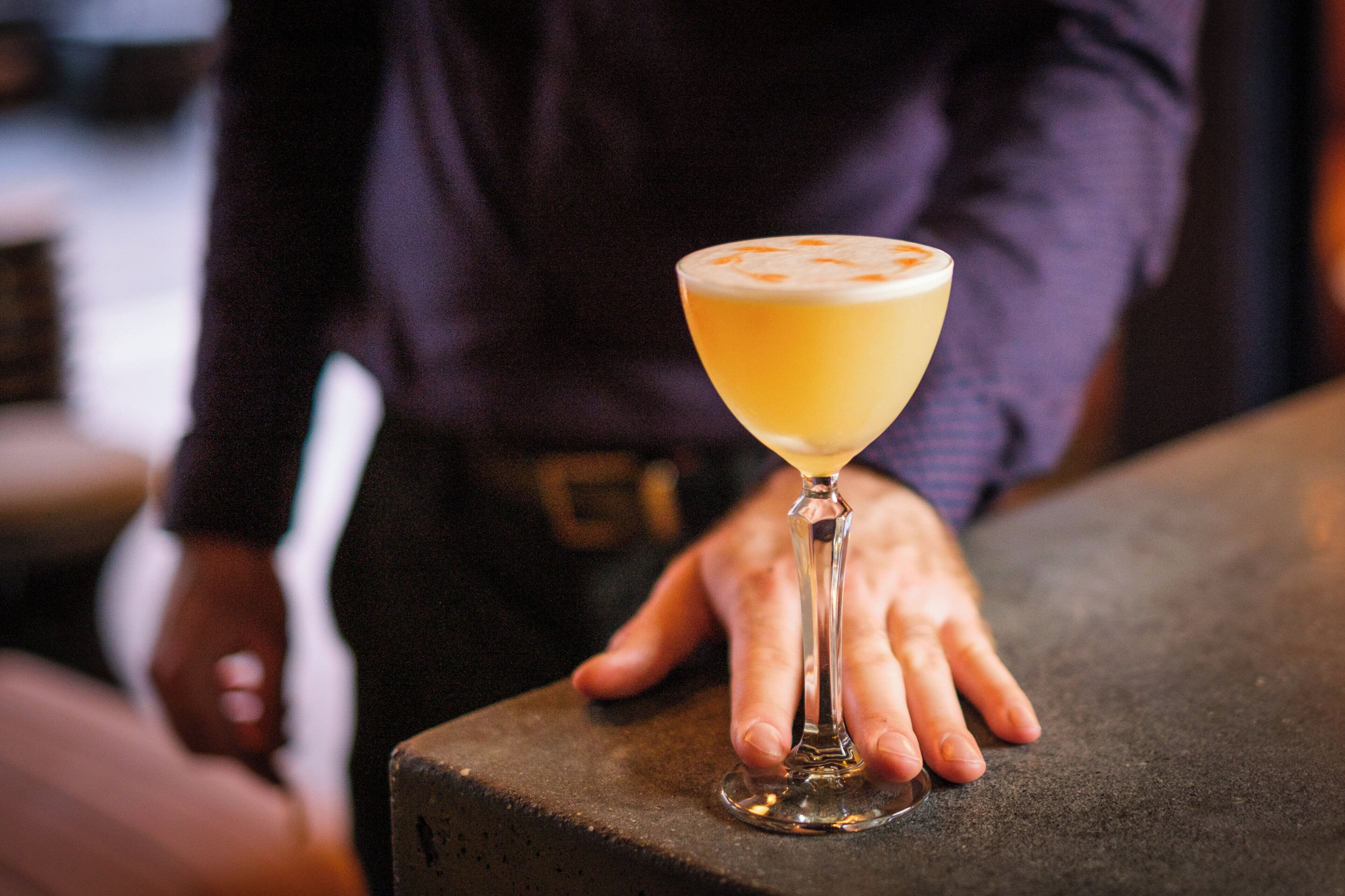 Ein Cocktail im Martiniglas auf einer Bar.