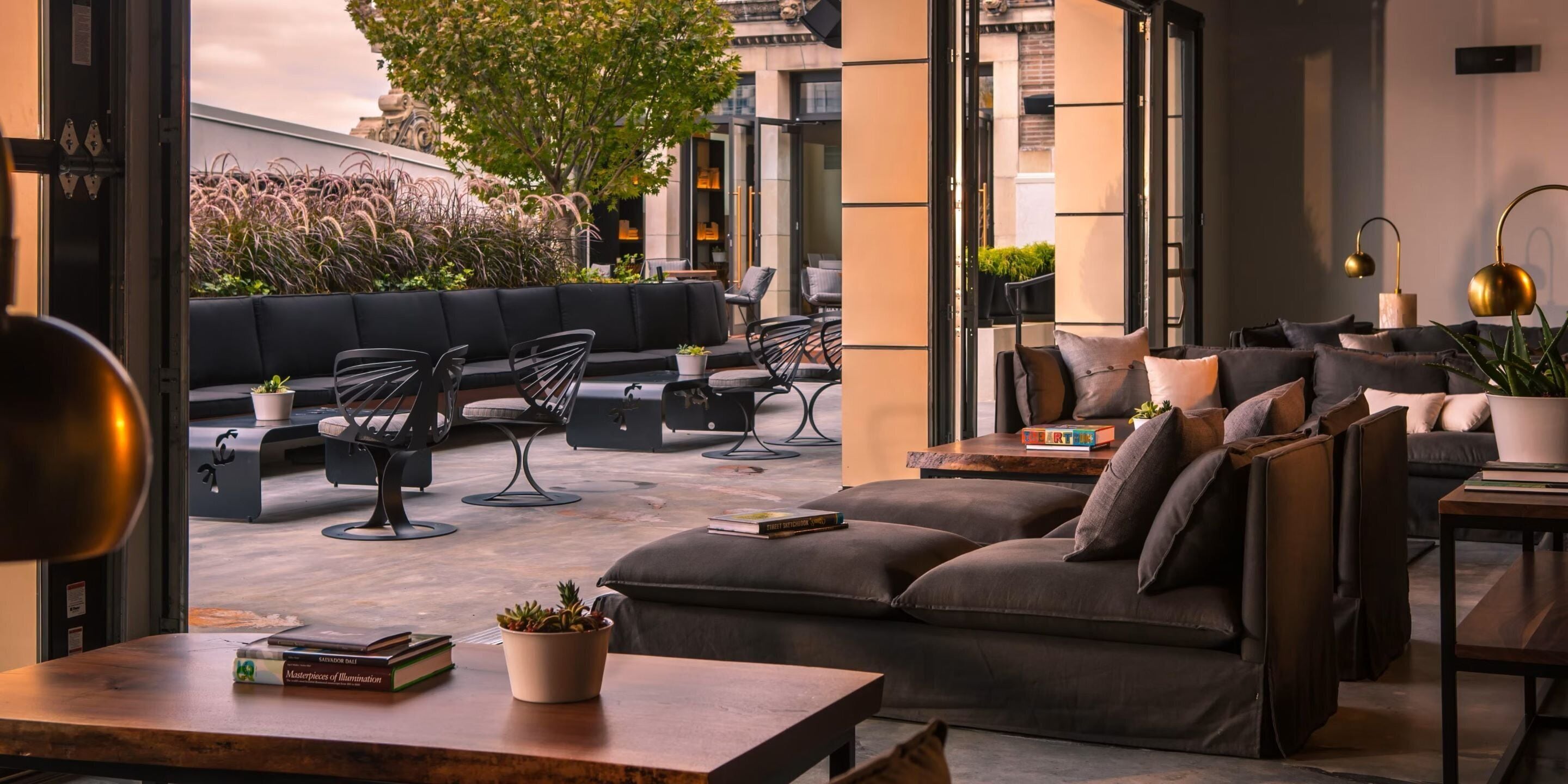 Een moderne buitenruimte met banken, stoelen en tafels, met boeken en planten.