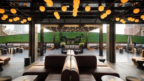 Un espace extérieur aménagé avec des meubles modernes, un mur végétal et des luminaires suspendus.