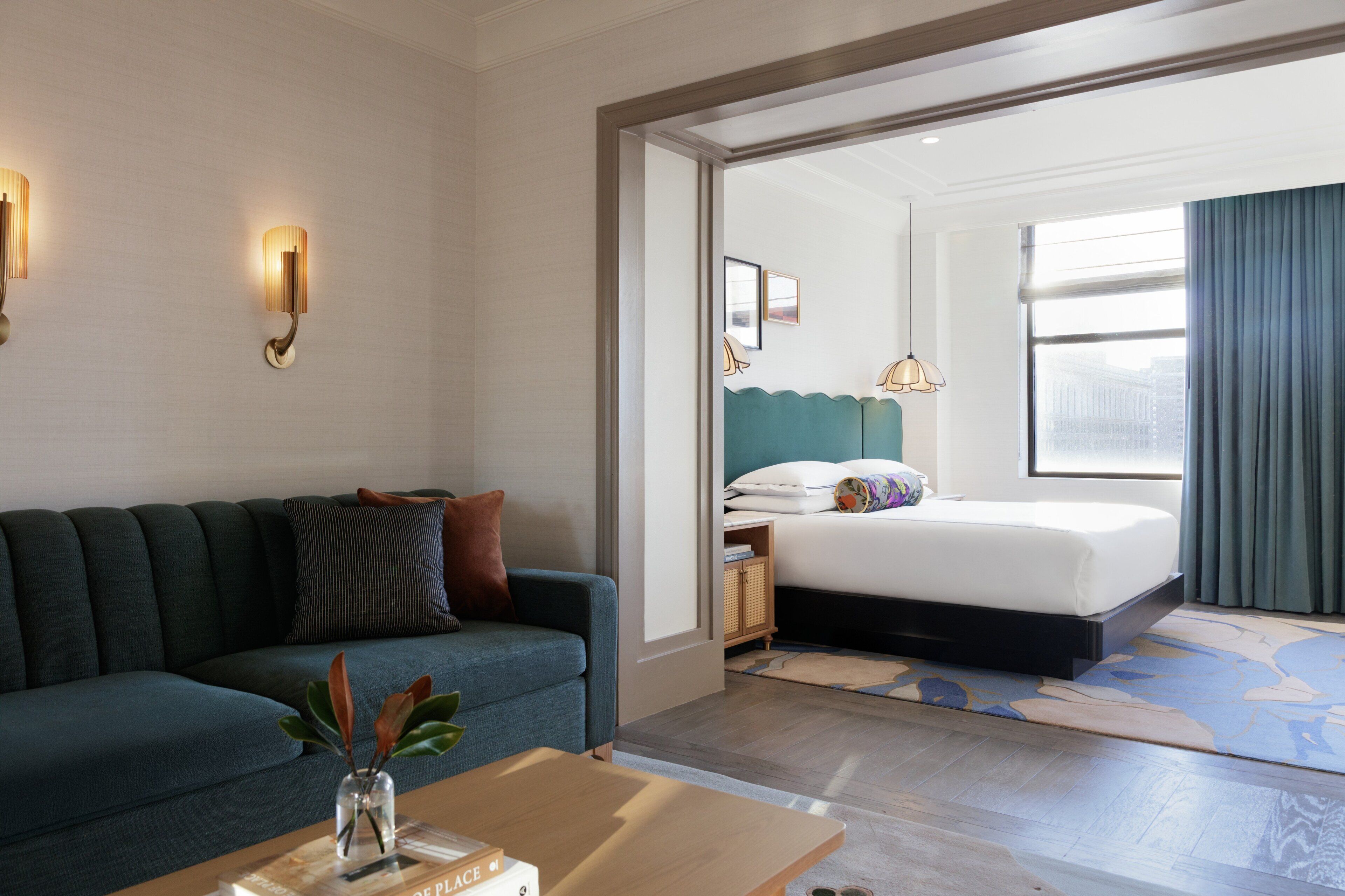 Un hotel moderno con sofá, cama, mesita de noche y vistas a la ciudad.