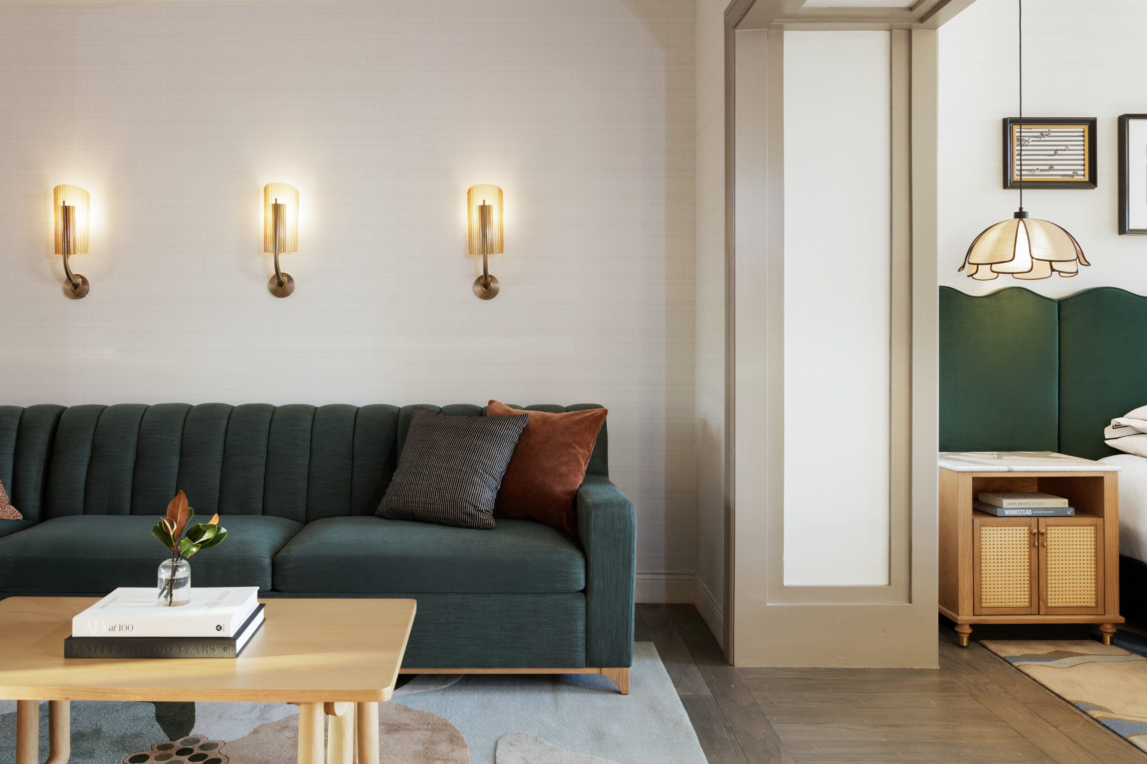 A modern living room with a green sofa, a wooden coffee table, and wall-mounted lighting.