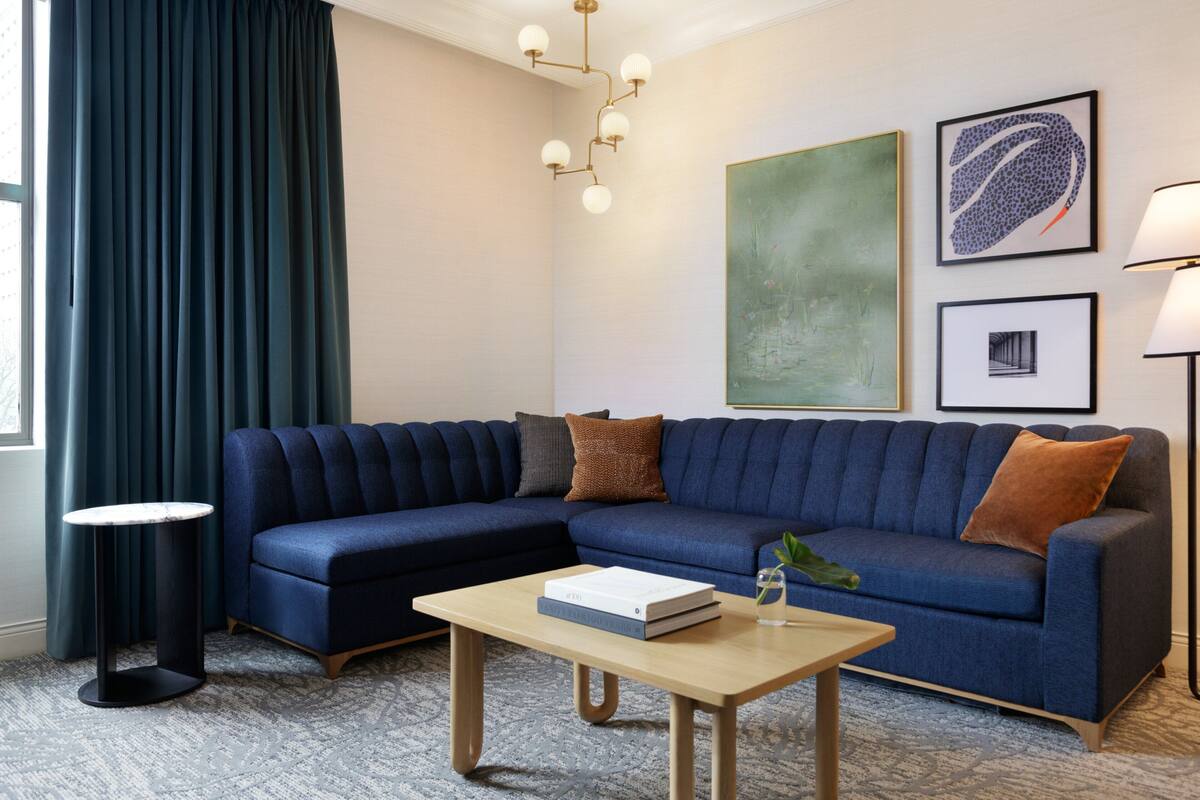 A modern living room with a sectional sofa, a round coffee table, a floor lamp, and artwork on the walls.