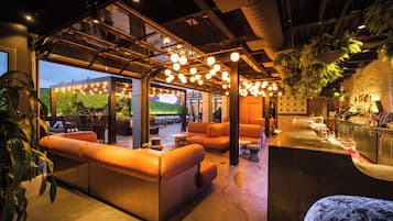 A modern bar area with leather seating, a counter, and hanging plants.