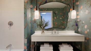 A bathroom with a white sink, two wall-mounted lights, a mirror, and floral wallpaper.