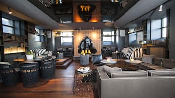 A modern lounge area with a central seating arrangement, bookshelves, and a unique wall-mounted sculpture.