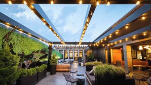Une terrasse extérieure avec des sièges, un mur végétal et des guirlandes lumineuses.