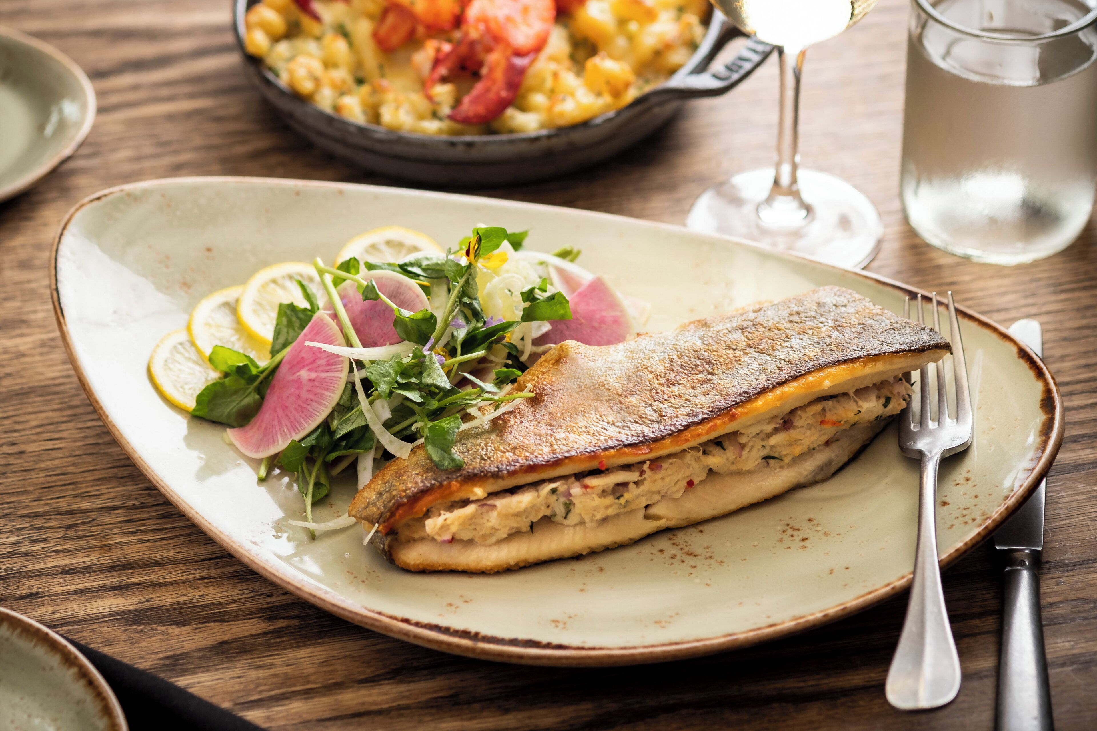 A plate with a fish fillet sandwich and a side salad.