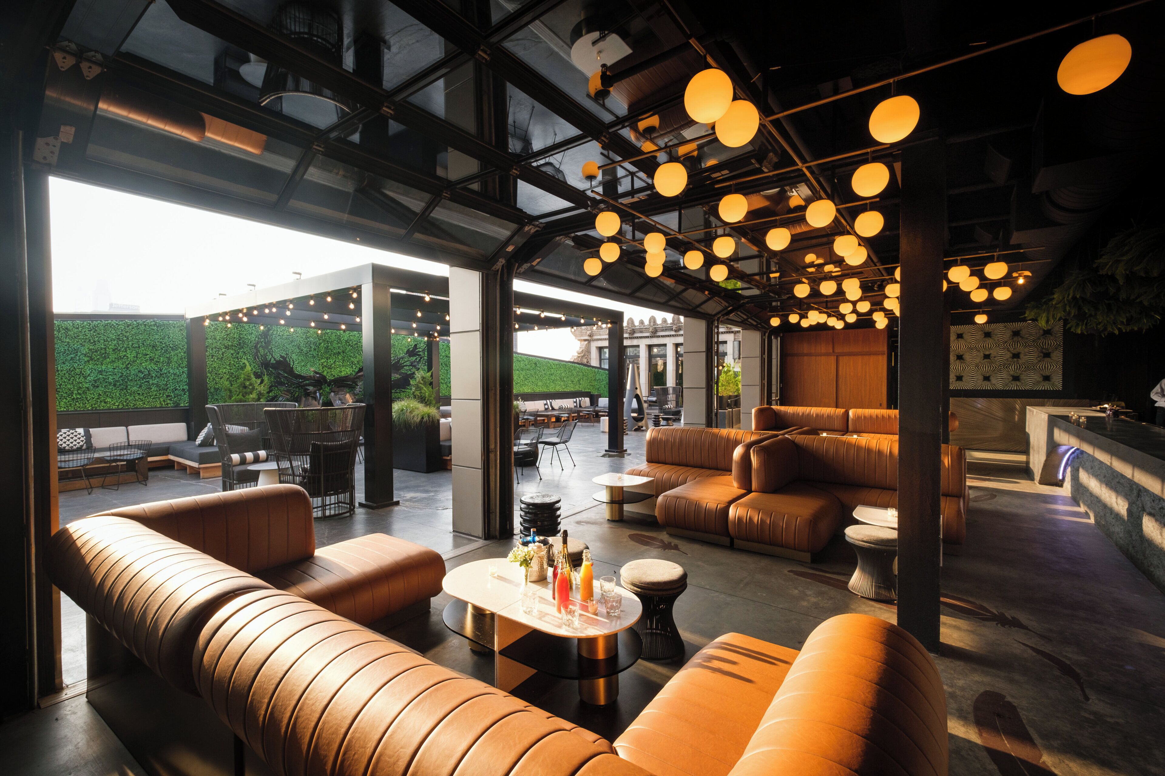 A modern lounge area with leather sofas, a coffee table with drinks, and pendant lighting.